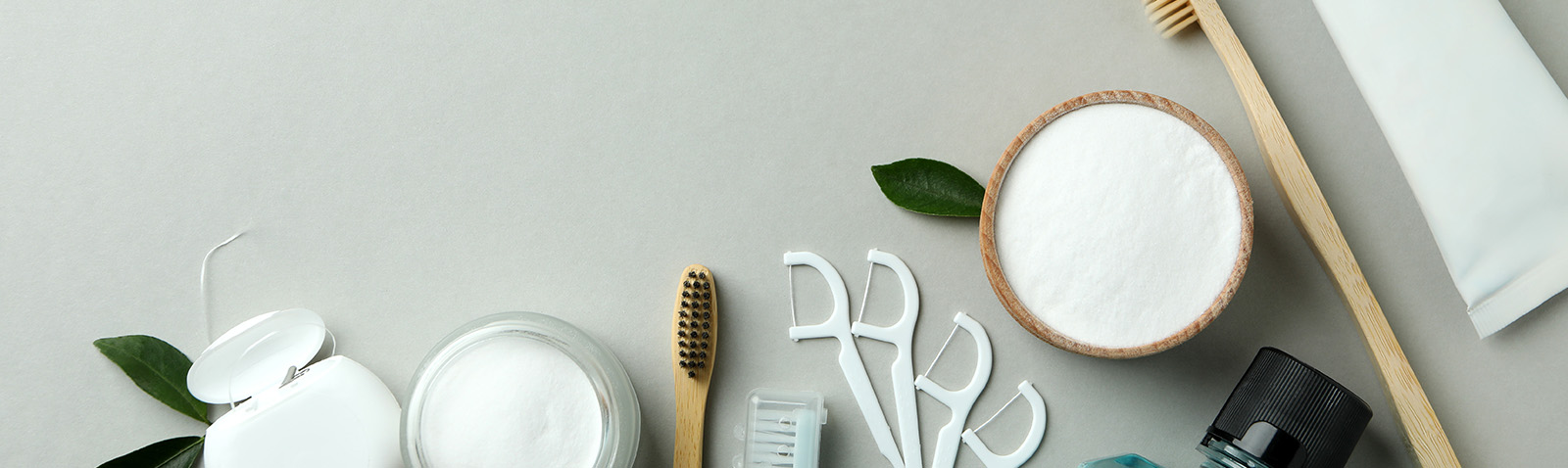 A collection of cosmetic items including brushes, bowls, and other personal care products displayed on a table with a green leaf motif.